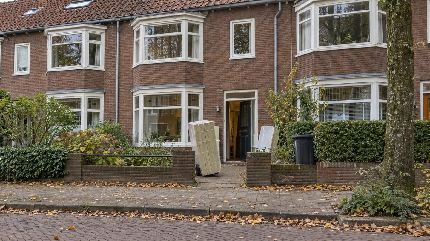 Pak isolatieplaten op een steekwagen voor de open voordeur van een bakstenen rijtjeshuis in de herfst